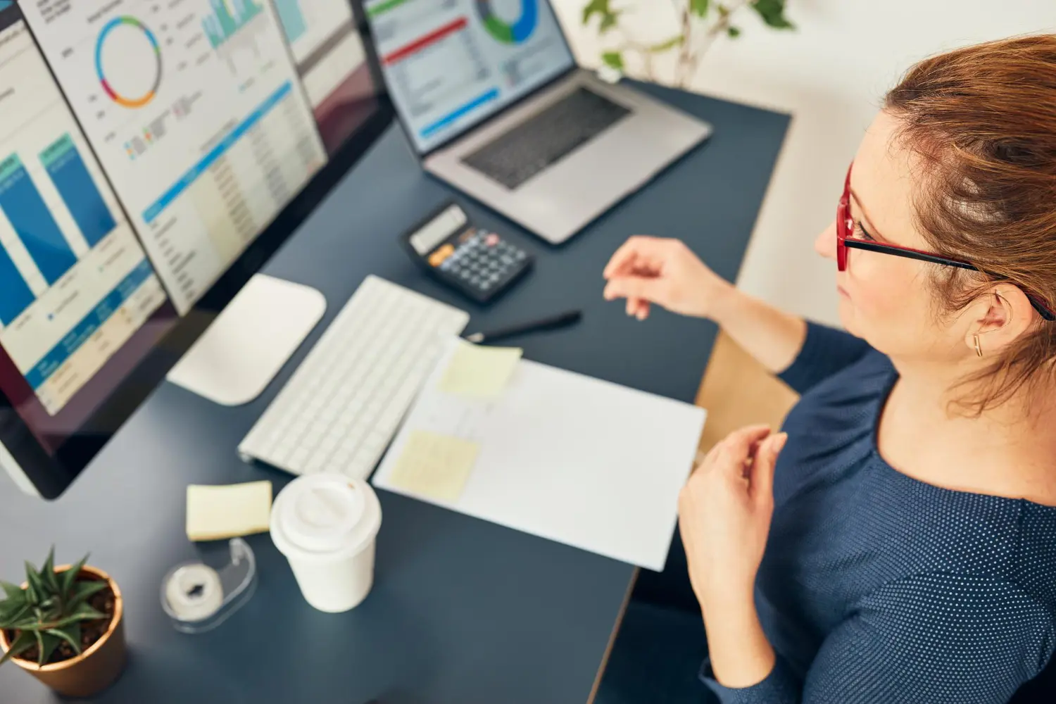 Profissional trabalhando em mesa de escritório enquanto faz a gestão de tarefas na contabilidade