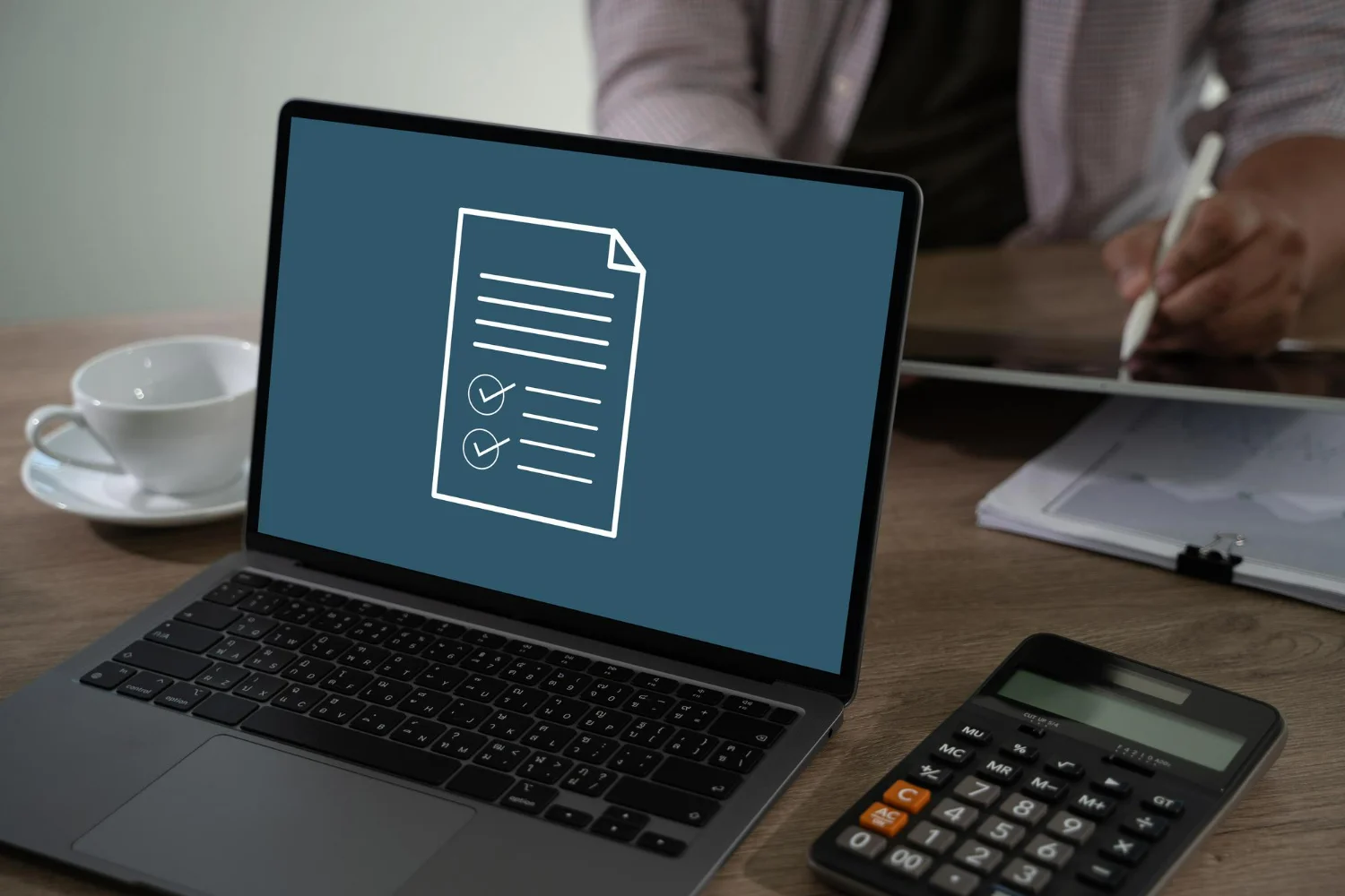 Imagem de uma calculadora ao lado de um notebook, com um documento na tela simbolizando a atualização da NFS-e.