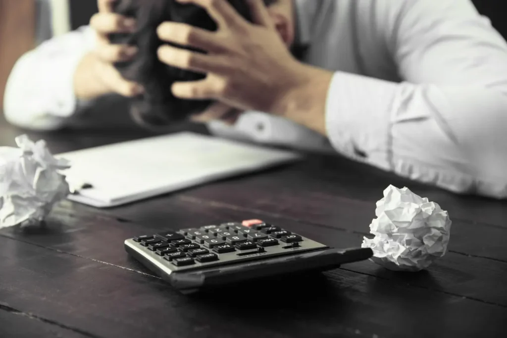 Imagem de um homem com expressão de desespero ao fazer contas, simbolizando os erros fiscais na contabilidade.