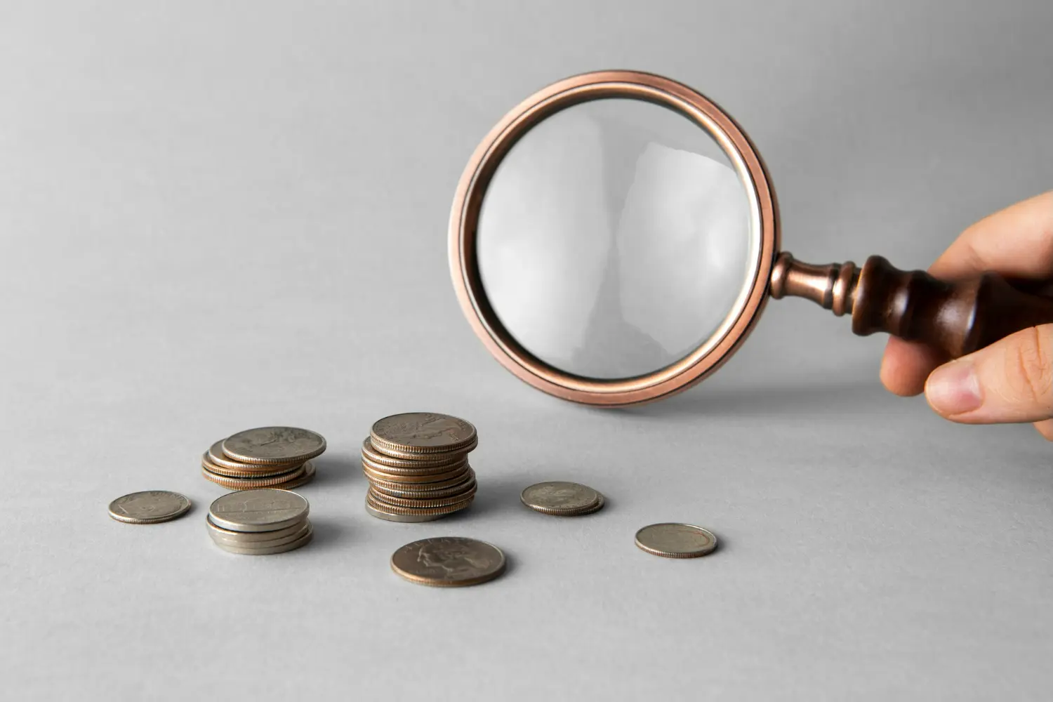 Imagem de uma lupa sobre moedas, simbolizando a reforma tributária e suas mudanças na contabilidade.