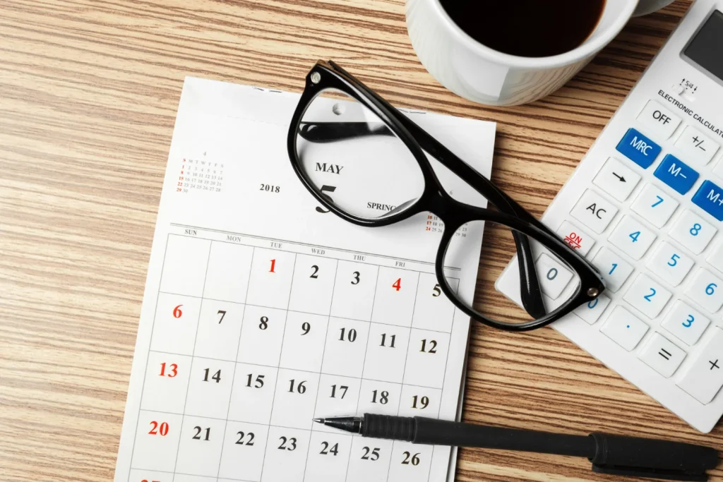 Imagem de uma calculadora e um calendário sobre a mesa de trabalho, simbolizando o controle de prazos contábeis.
