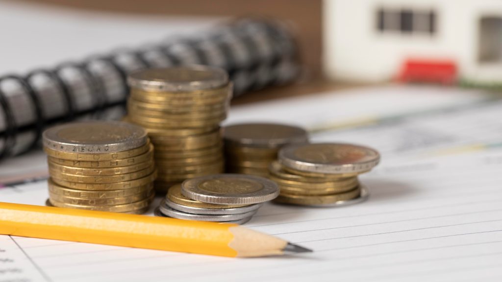 Pilhas de moedas sobre um caderno de anotações, simbolizando as estratégias para proteger o crédito tributário.