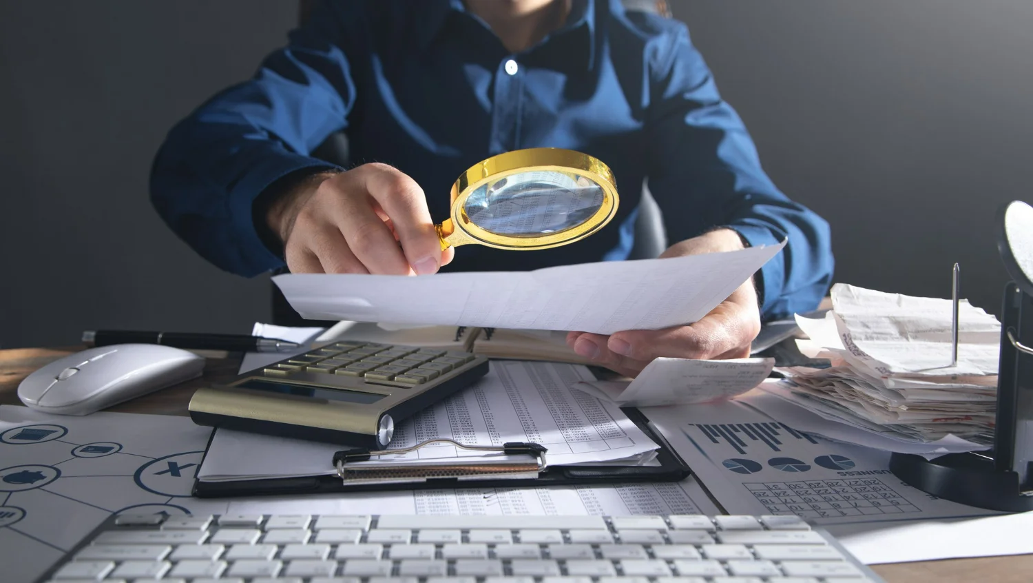 Homem utilizando uma lupa para checar informações fiscais em documento e regularizar pendências na Receita Federal.