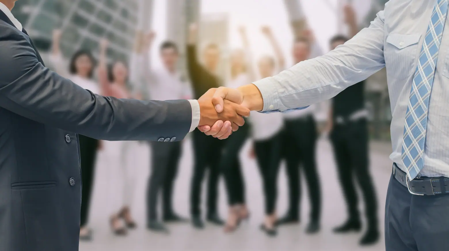 Dois homens apertando as mãos em frente a um grupo de trabalhadores, simbolizando um acordo de convenção coletiva trabalhista.