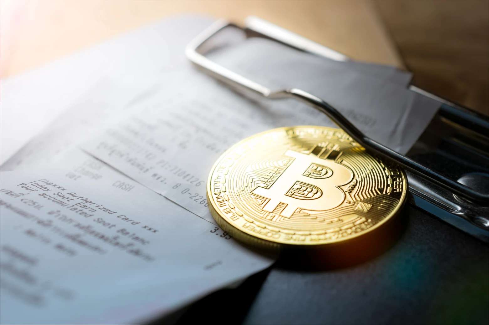 Moeda de bitcoins em cima de documentos de declaração de criptoativos