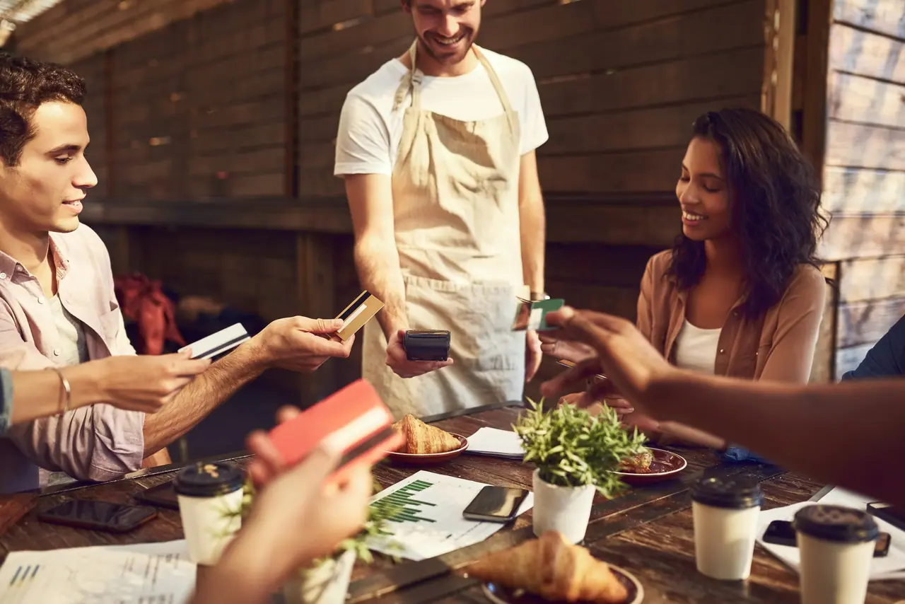 Grupo de colegas de trabalho pagam restaurante com cartões das novas regras do vale-alimentação